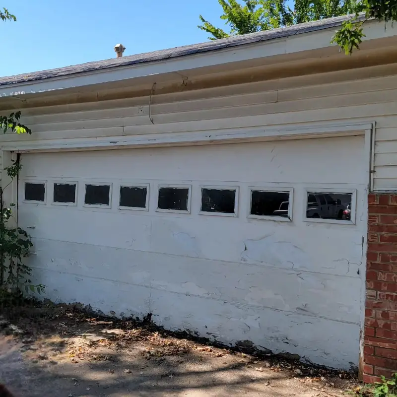 A worn, peeling garage door before replacement